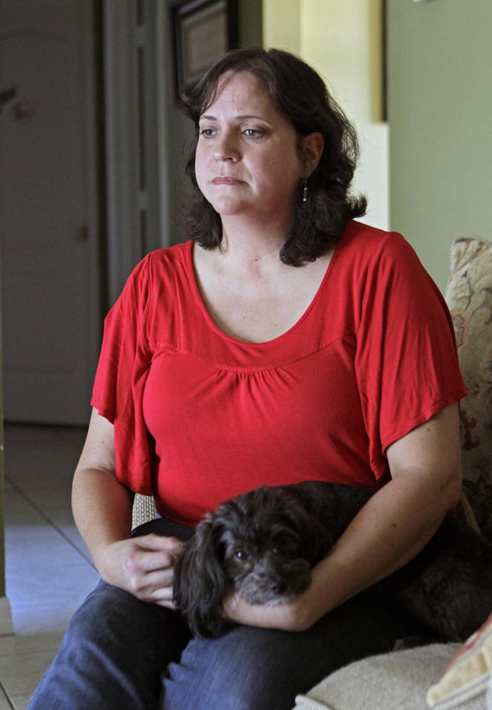 In this Tuesday, July 31, 2012 photo, Marisol Walker sits with her dog in her home in Ocoee, Fla. Walker is fighting to keep the home that she and her husband bought about a year before his business collapsed. Walker says they haven't been able to pay the mortgage in 1½ years. She works part-time, while her husband is trying to restart his business. She finds the current political debate alienating. "I listen to politicians today and it makes me angry," she says. "I want them to explain to me how two willing workers are struggling and have lost everything. ... I don't think it matters who's running the government. I don't see how any of them are going to help any of us living in the real world." (AP Photo/John Raoux)