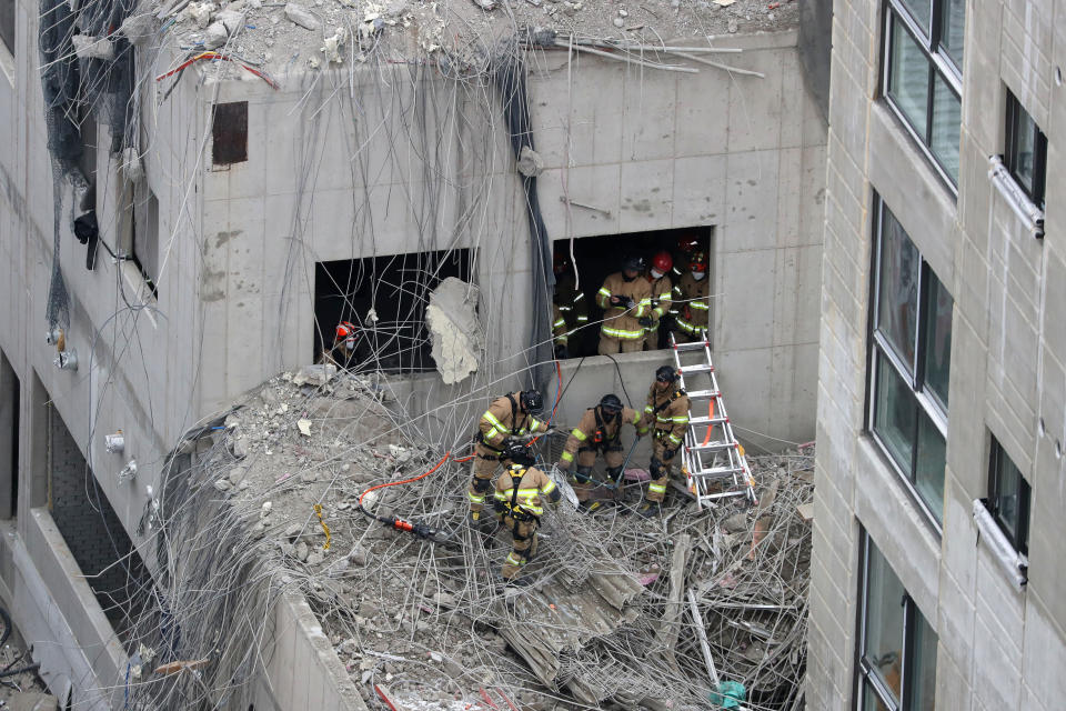 Rescuers search for workers who went missing in an apartment construction accident in Gwangju, South Korea, Thursday, Jan. 13, 2022. South Korean rescuers on Thursday located a man under a pile of debris and broken concrete at the construction site of a 39-floor building that partially collapsed three days earlier, leaving six workers missing, officials said. (Chung Hoe-sung /Yonhap via AP)