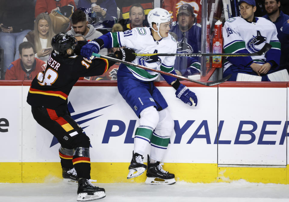 Vancouver Canucks defenseman Nikita Zadorov, right, swats away a check from Calgary Flames forward A.J. Greer during the first period of an NHL hockey game, Saturday, Dec. 2, 2023 in Calgary, Alberta. (Jeff McIntosh/The Canadian Press via AP)