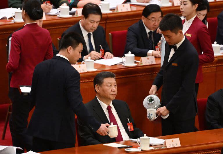 Trabajadores reponen las tazas de té del presidente chino Xi Jinping durante la sesión de apertura del Congreso Nacional del Pueblo (NPC) en el Gran Salón del Pueblo en Pekín el 5 de marzo de 2024.