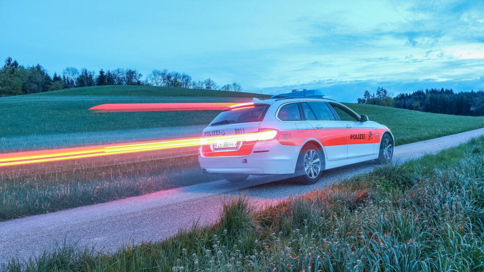 BMW 5 Series Swiss police wagon driving on road.