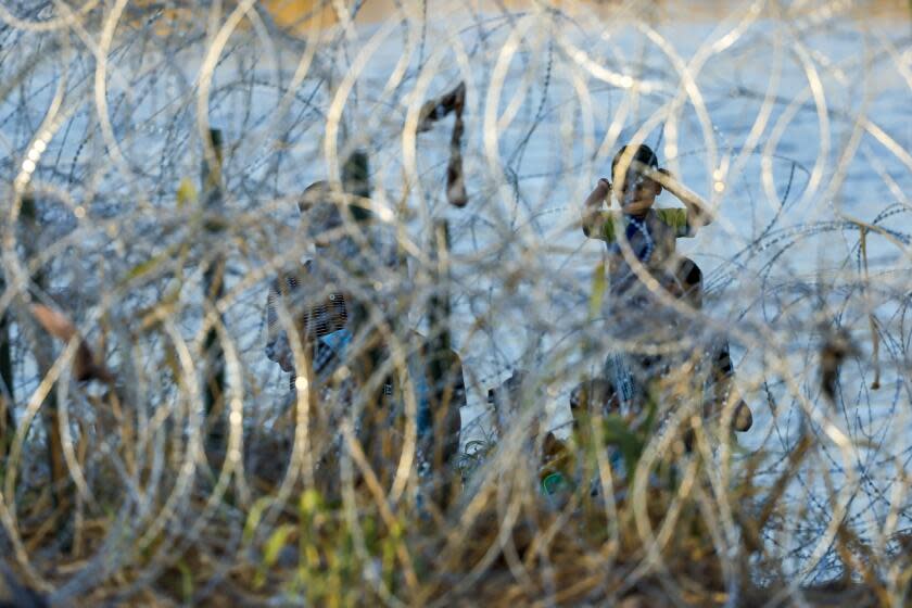 Eagle Pass, Texas, Thursday, September 21, 2023 - Migrants gather behind razor wire after crossing the Rio Grande into Eagle Pass. (Robert Gauthier/Los Angeles Times)