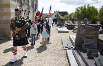 British expatriate Steven Oldrid, right, is led by a bagpiper as he directs a D-Day ceremony of laying flowers and wooden crosses for WWII dead at the local war cemetery in Benouville, Normandy, France on Saturday, June 6, 2020. Due to coronavirus measures many relatives and veterans will not make this years 76th anniversary of D-Day. Oldrid will be bringing it to them virtually as he places wreaths and crosses for families and posts the moments on his facebook page. (AP Photo/Virginia Mayo)