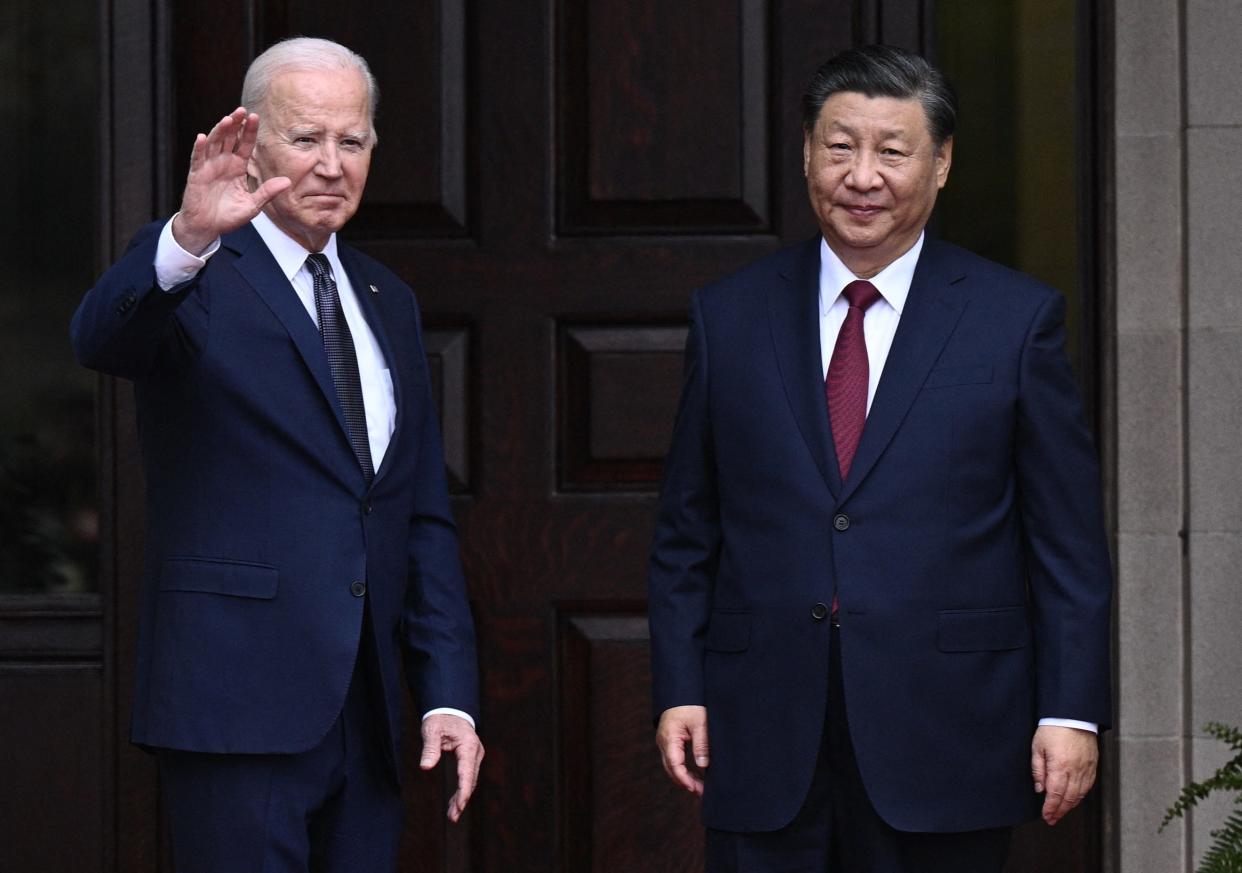 Joe Biden and Xi Jinping standing together, with Biden waving.