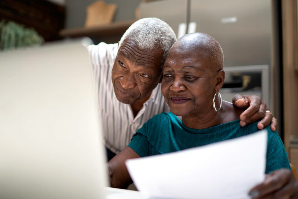An elderly man and wife look at medicare options on their laptop. 