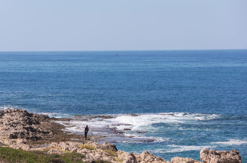 A fisherman dangles his line to catch fish, in Naqoura, near the Lebanese-Israeli border