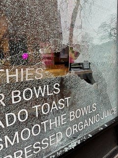 A broken storefront window outside Burlington business Thorn + Roots.