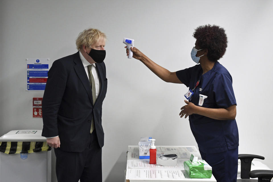 Britain's Prime Minister Boris Johnson has his temperature checked during a visit to Chase Farm Hospital in north London, Monday Jan. 4, 2021. Johnson warned Sunday that more onerous lockdown restrictions in England are likely in the coming weeks as the country reels from a coronavirus variant that has pushed infection rates to their highest recorded levels. (Stefan Rousseau/Pool Photo via AP)