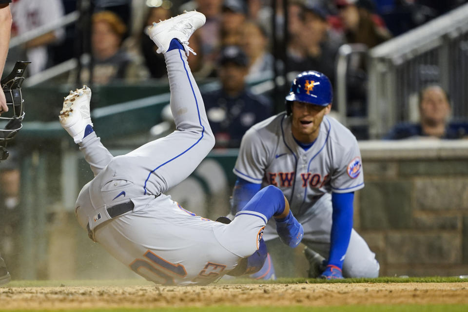 New York Mets' Eduardo Escobar (10) rolls over after scoring on a sacrifice fly with Brandon Nimmo at right, during the sixth inning of a baseball game against the Washington Nationals at Nationals Park, Tuesday, May 10, 2022, in Washington. (AP Photo/Alex Brandon)
