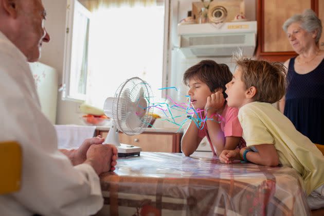 Boys standing in front of a fan and enjoy cool waves while their grandparents looking at them and smilling (Photo: Thanasis Zovoilis via Getty Images)