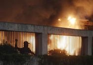 Student protesters throw stones to riot police as toll gate burn in the background during a protest outside the parliament in Jakarta, Indonesia Tuesday, Sept. 24, 2019. Police fired tear gas and water cannons Tuesday to disperse thousands of rock-throwing students protesting a new law that they said has crippled Indonesia's anti-corruption agency.(AP Photo/Achmad Ibrahim)