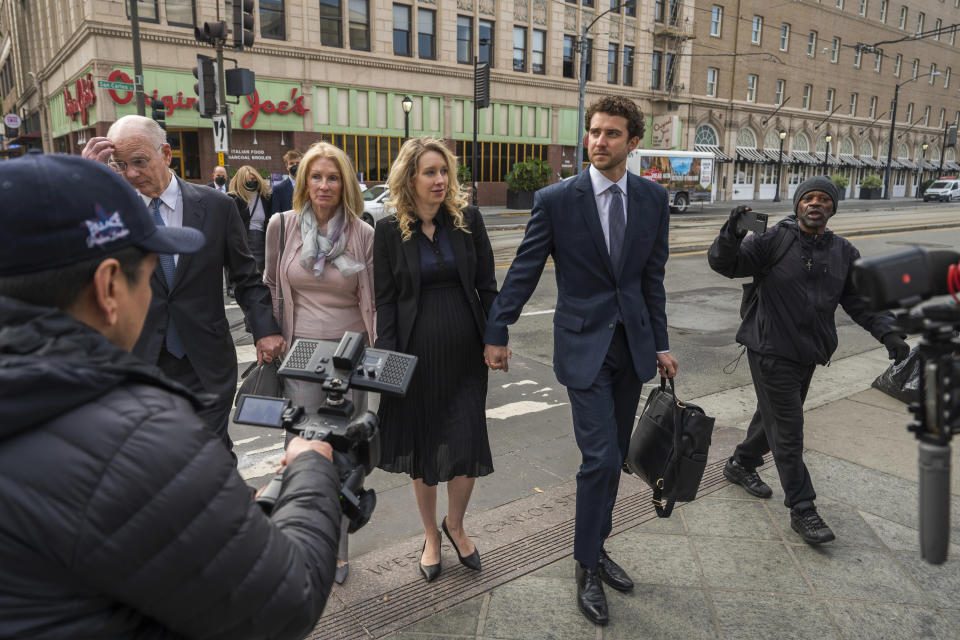 Theranos founder and CEO Elizabeth Holmes, center, walks into federal court in San Jose, Calif., Friday, Nov. 18, 2022. A federal judge will decide whether Holmes should serve a lengthy prison sentence for duping investors and endangering patients while peddling a bogus blood-testing technology. (AP Photo/Nic Coury)