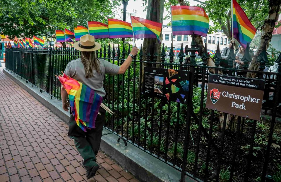 A National Park Service ranger place rainbow flags, representing LBGTQ pride, along fencing around Christopher Park, Friday June 14, 2019, in New York's Greenwich Village. June is Pride Month, celebrated each year to mark the 1969 Stonewall rebellion, a series of violent confrontations between the gay community and police, that occurred near the park at a gay bar called the Stonewall Inn.