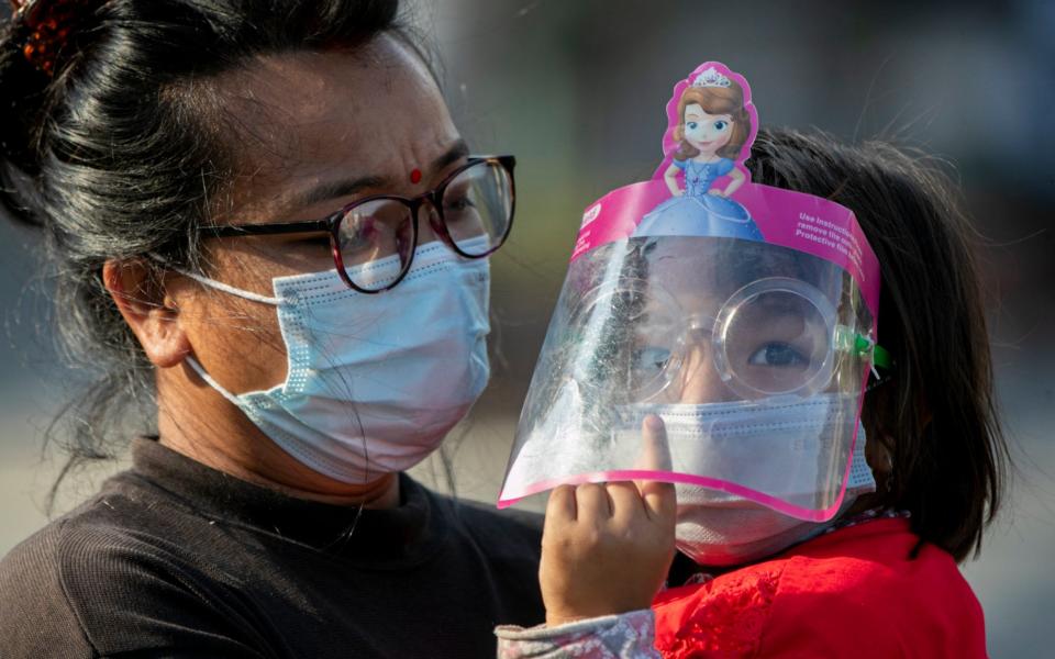 A Nepalese woman and her daughter wearing face masks at the Rato Machindranath chariot festival in Lalitpur, Nepal -  Niranjan Shrestha / AP