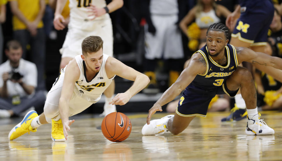 Iowa guard Jordan Bohannon, left, fights for a loose ball with Michigan guard Zavier Simpson during the first half of an NCAA college basketball game Friday, Feb. 1, 2019, in Iowa City, Iowa. (AP Photo/Charlie Neibergall)