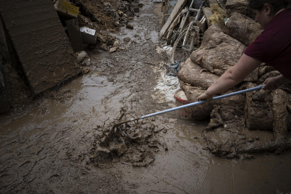 A woman tries to clean the mud in front of her house in Bad Neuenahr-Ahrweiler, Germany, Monday July 19, 2021. More than 180 people died when heavy rainfall turned tiny streams into raging torrents across parts of western Germany and Belgium, and officials put the death toll in Ahrweiler county alone at 110. (AP Photo/Bram Janssen)