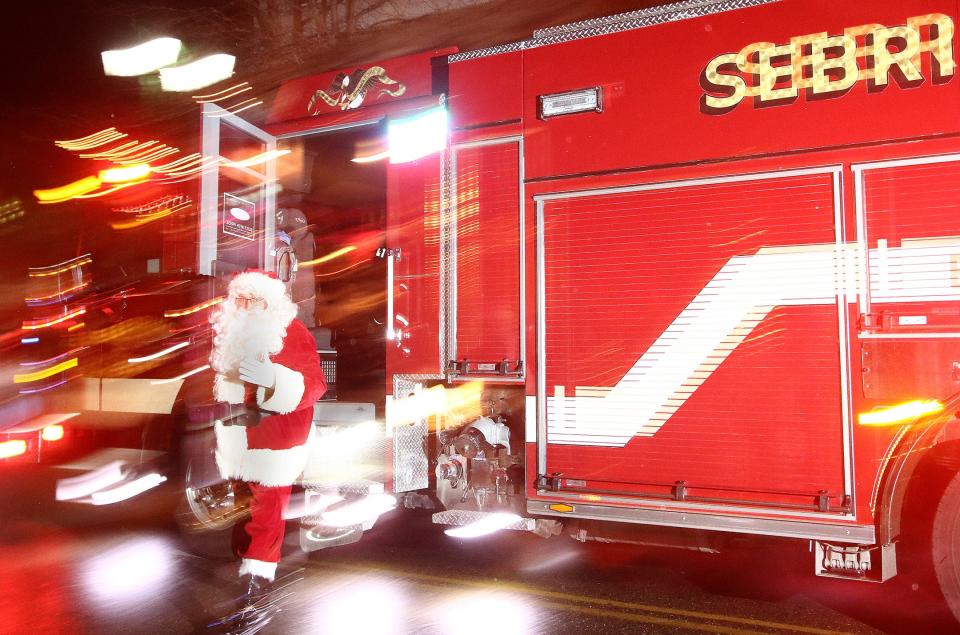 Santa climbs down from a Sebring Fire Department vehicle to greet a crowd Saturday night before a lighting ceremony at Harvest Park.