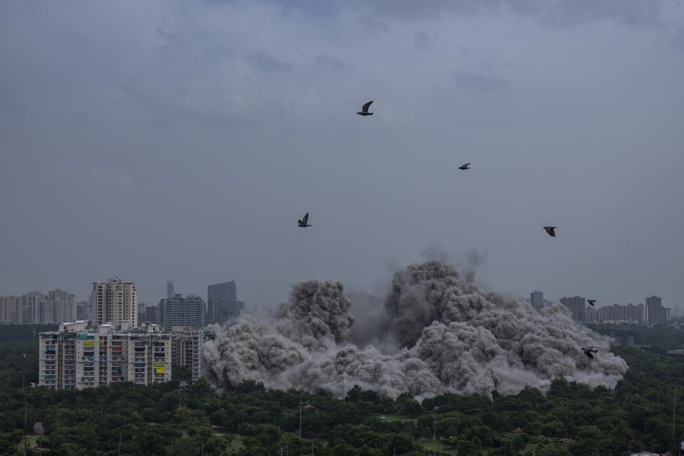 Clouds of dust rise as twin high-rise apartment towers are leveled in a controlled demolition in Noida, on the outskirts of New Delhi, India, Sunday, Aug. 28, 2022. The country's top court declared them illegal for violating building norms. The 32-story and 29-story towers, constructed by a private builder were yet to be occupied and became India's tallest structures to be razed to the ground. (AP Photo/Altaf Qadri)