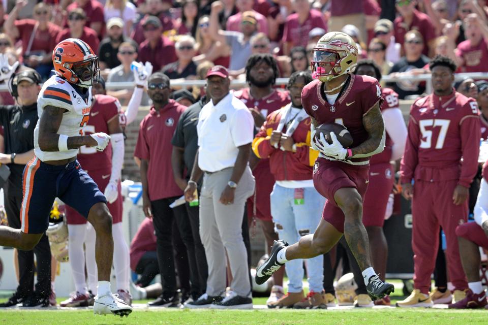 Florida State wide receiver Keon Coleman (4) catches a pass in front of Syracuse defensive back Isaiah Johnson (3) and runs for a 58-yard touchdown during the first half of an NCAA college football game, Saturday, Oct. 14, 2023, in Tallahassee, Fla.