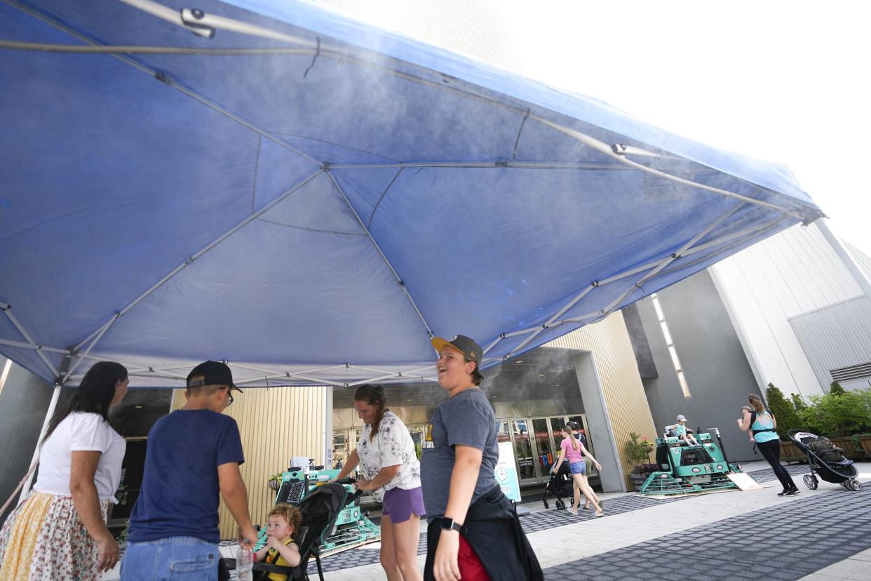 Visitors to COSI cool off in a misting tent as they walk in the front door of the science center in Columbus on June 14. On Tuesday, it's expected to be another hot one, despite rain, as heat index values are predicted to be as high as 100 degrees.