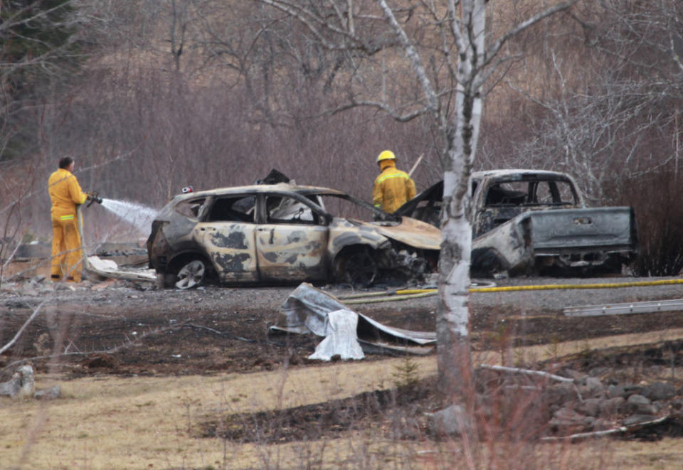 burned vehicles abandoned in the woods and firemen with water hoses