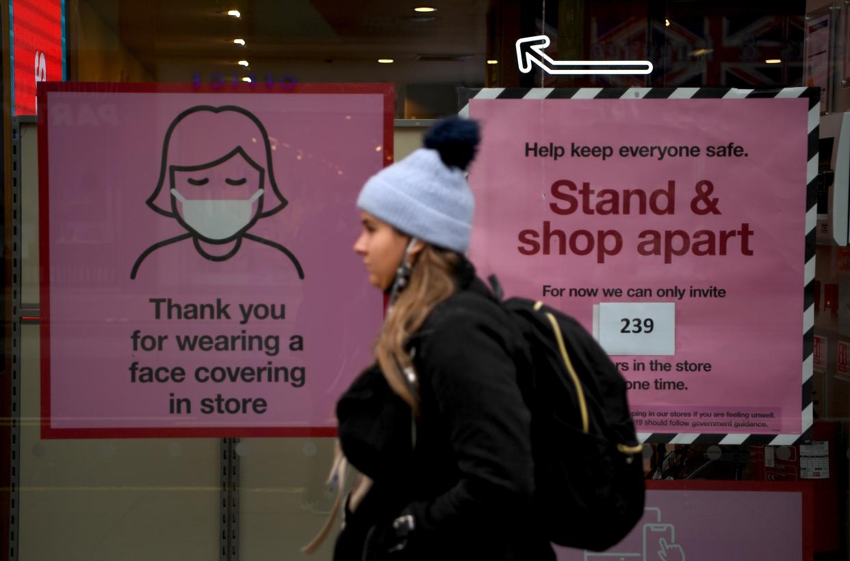 A pedestrian walks past posters advising customers to wear a face mask or covering due to the COVID-19 pandemic, as she walk past a temporarily closed-down shop on an almost deserted Oxford Street in London on November 26, 2020. - Britain's government on Wednesday unveiled plans to slash the foreign aid budget to help mend its coronavirus-battered finances, prompting one minister to quit and defying impassioned calls to protect the world's poorest people. (Photo by DANIEL LEAL-OLIVAS / AFP) (Photo by DANIEL LEAL-OLIVAS/AFP via Getty Images)