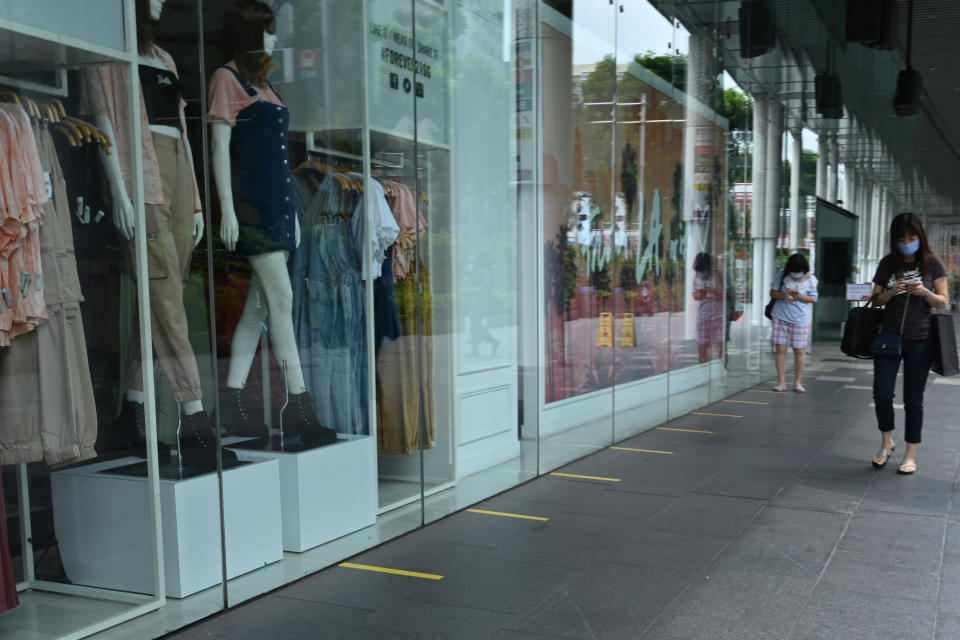 People, wearing face masks as a preventive measure against the spread of the COVID-19 novel coronavirus, walk past closed retail shops along the Orchard Road shopping belt in Singapore on May 6, 2020. (Photo by Roslan RAHMAN / AFP) (Photo by ROSLAN RAHMAN/AFP via Getty Images)