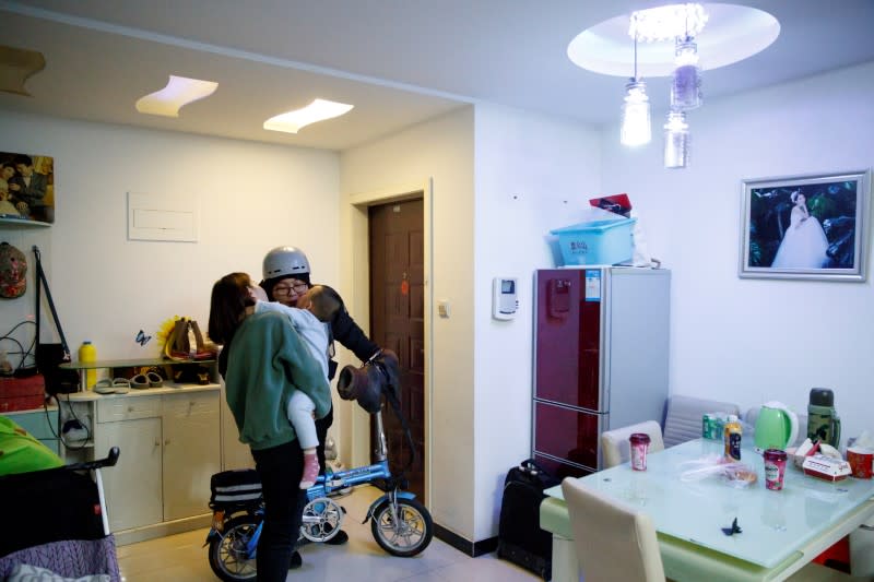 Liu Pengfei, a substitute driver of ride-hailing service platform DiDi Chuxing, kisses his wife Su Anning and son Liu Xuanming goodbye before leaving his apartment for his night shift in Beijing