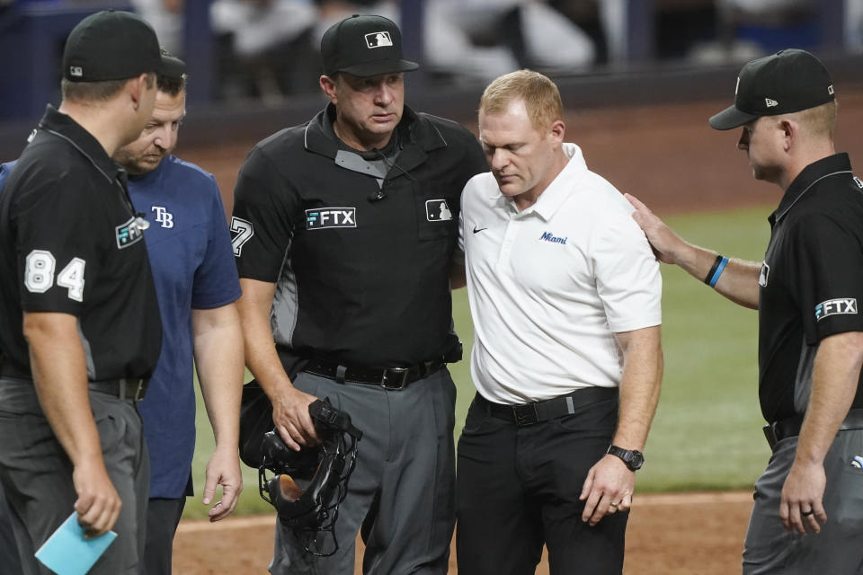 MLB home plate umpire Jim Reynolds is assisted off the field after he was hit by a pitch in the eighth inning of a baseball game against the Miami Marlins, Tuesday, Aug. 30, 2022, in Miami. (AP Photo/Marta Lavandier)