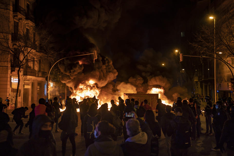 Demonstrators gather near a burning barricade during clashes with police following a protest condemning the arrest of rap singer Pablo Hasél in Barcelona, Spain, Thursday, Feb. 18, 2021. Protests over the imprisonment of a rapper convicted for insulting the Spanish monarchy and praising terrorist violence have morphed for the third night in a row into rioting. Pablo Hasél began this week to serve a 9-month sentence in a northeastern prison. (AP Photo/Felipe Dana)