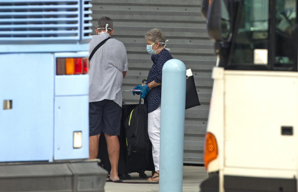 CORRECTS THE MONTH - Coral Princess cruise passengers wait to board the bus at PortMiami as the coronavirus pandemic continues on Sunday, April 5, 2020 in Miami. (David Santiago/Miami Herald via AP)