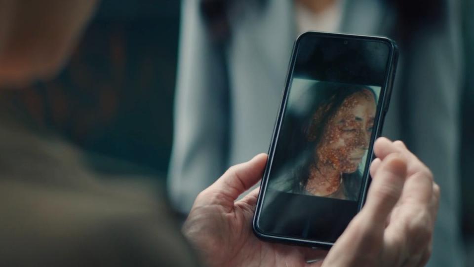 Mallory holds a cellphone showing a dead, infected supe on Gen V