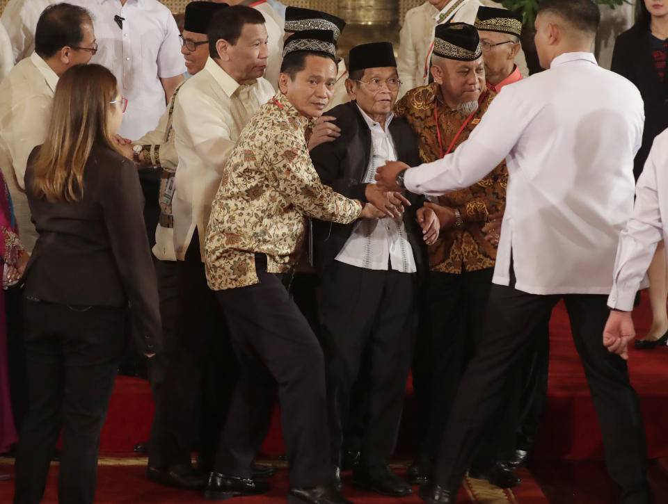 President Rodrigo Duterte, third from left, helps in assisting Ghazali Jaafar, Vice-chair for Political Affairs and Chair of the Bangsamoro Transition Commission, after briefly falling following oath-taking ceremony for the creation of the Bangsamoro Transition Authority or BTA at the Presidential Palace in Manila, Philippines Friday, Feb. 22, 2019. Some of the fiercest Muslim rebel commanders in the southern Philippines are in Manila to be sworn in as administrators of a new Muslim autonomy region in a delicate milestone to settle one of Asia's longest-raging rebellions. Several commanders, including Commander Bravo, long wanted for deadly attacks were given safety passes to be able to travel to Manila and join the ceremony.(AP Photo/Bullit Marquez)