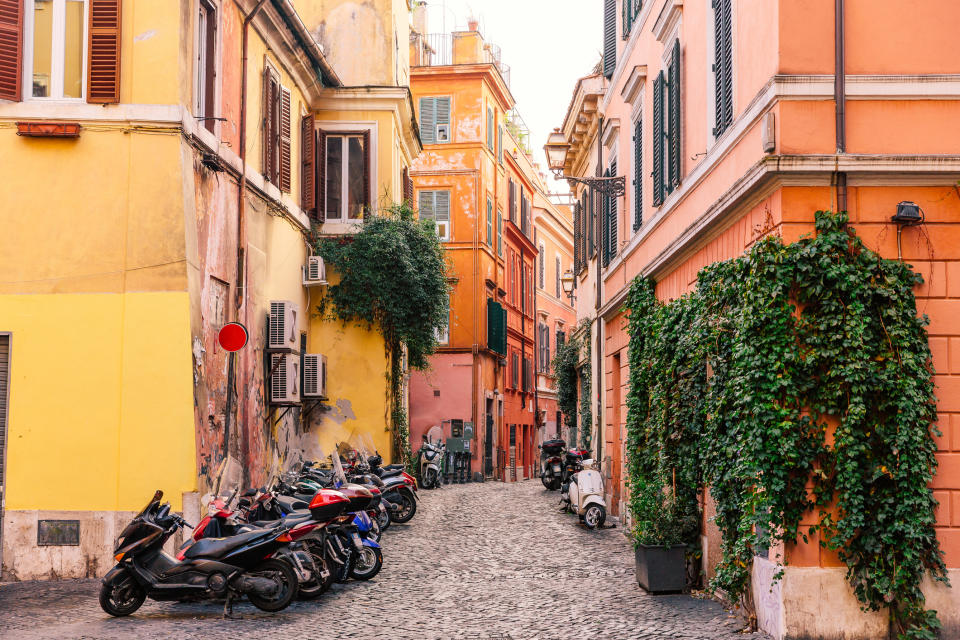 Narrow cobblestone street lined with motorcycles and ivy-covered buildings