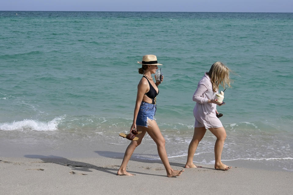 People walk along the beach, Monday, Nov. 15, 2021, in Miami Beach, Fla. Cooped-up tourists eager for a taste of Florida's sandy beaches, swaying palm trees and warmer climates are visiting the Sunshine State in droves, topping pre-pandemic levels in recent months. (AP Photo/Lynne Sladky)