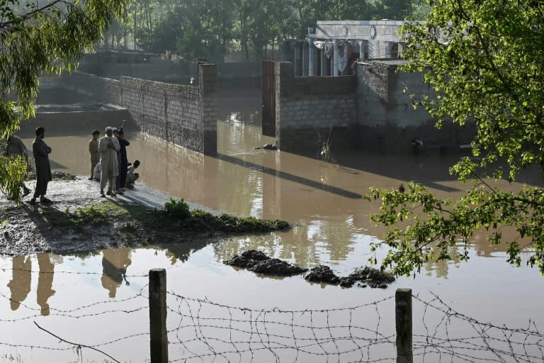 Residents stand outside their flooded homes following heavy rains in Charsadda district of Khyber Pakhtunkhwa province on April 17, 2024 (Abdul MAJEED)