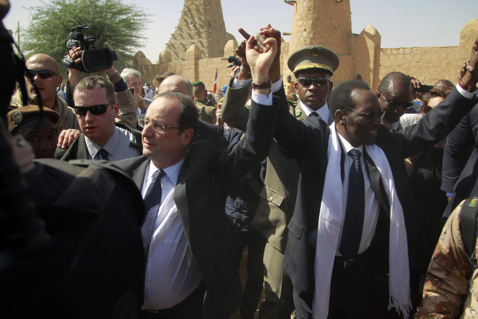 FILE - French President Francois Hollande holds hands with Mali's interim President Dioncounda Traoré in Timbuktu, Mali, Feb. 2, 2013. In Sept. 2023, France's waning influence in coup-hit Africa appears clear while few remember their former colonizer. (AP Photo/Jerome Delay, File)
