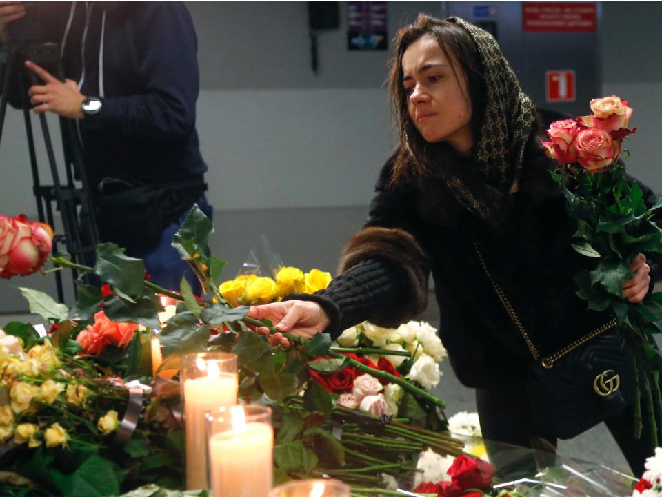 A woman lays flowers at a memorial of the flight crew members of the Ukrainian 737-800 plane that crashed on the outskirts of Tehran, at Borispil international airport outside in Kyiv, Ukraine, Saturday, Jan. 11, 2020. Ukraine's President Volodymyr Zelenskiy says that Iran must take further steps following its admission that one of its missiles shot down Ukrainian civilian airliner.  (AP Photo/Efrem Lukatsky)