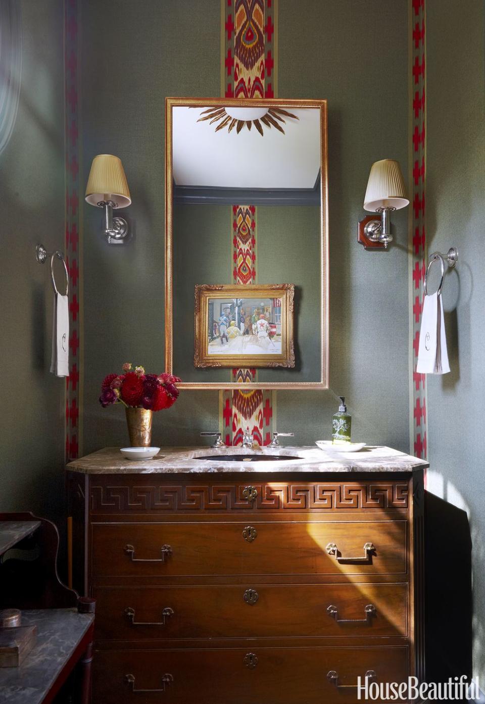 <p>Fitted with a marble top and an undermount basin, an 18th-century Swedish mahogany commode morphs into a vanity. Strips of antique ikat fabric, applied like wallpaper, keep the look current.</p>