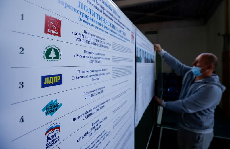 FILE PHOTO: A member of local election committee attaches a poster with pictures of candidates at a polling station ahead of parliamentary elections in the village of Ivolginsk