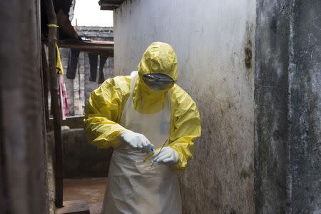 A health worker in protective equipment prepares a sample taken from the body of someone who is suspected to have died from Ebola virus, near Rokupa Hospital, Freetown October 6, 2014. REUTERS/Christopher Black/WHO/Handout via Reuters