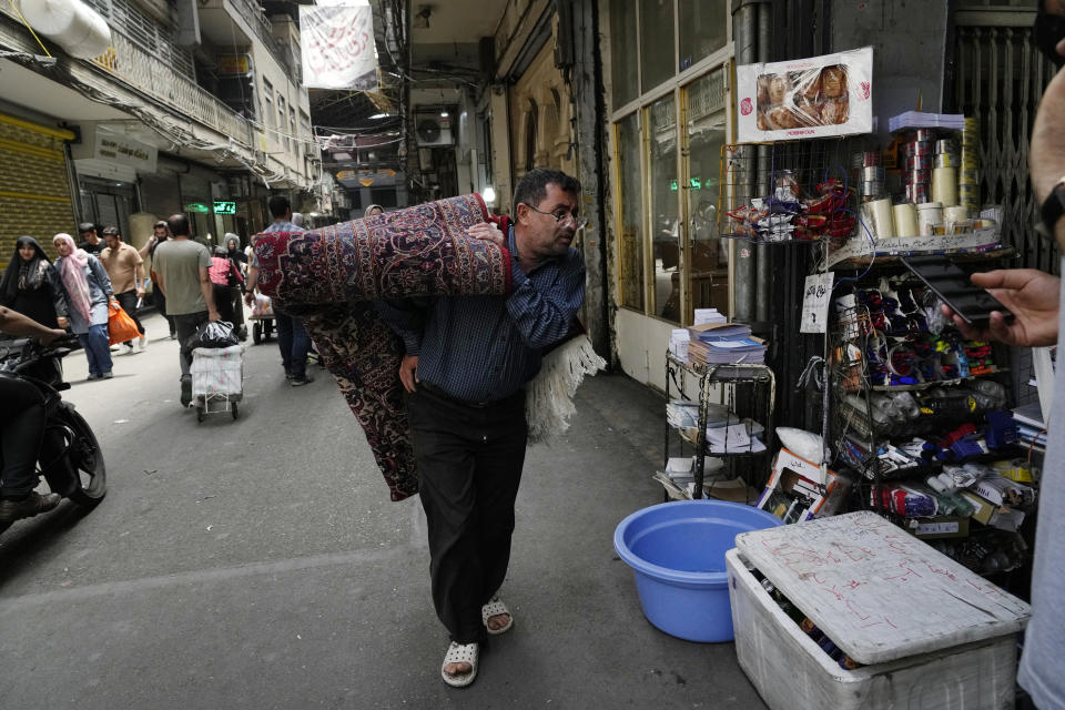 A man carries a carpet in the old main bazaar of Tehran, Iran, Thursday, June 13, 2024. The rise of the “Hamster Kombat” app in Iran highlights a harsher truth facing the Islamic Republic's economy ahead of its presidential election this week to replace the late President Ebrahim Raisi, who died in a helicopter crash in May. (AP Photo/Vahid Salemi)