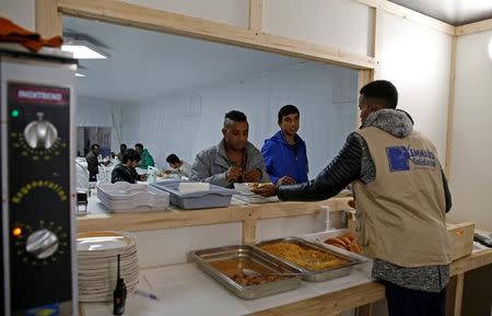 A charity worker serves food at the reception center for migrants and refugees near porte de La Chapelle in the north of Paris, France, November 25, 2016. REUTERS/Jacky Naegelen