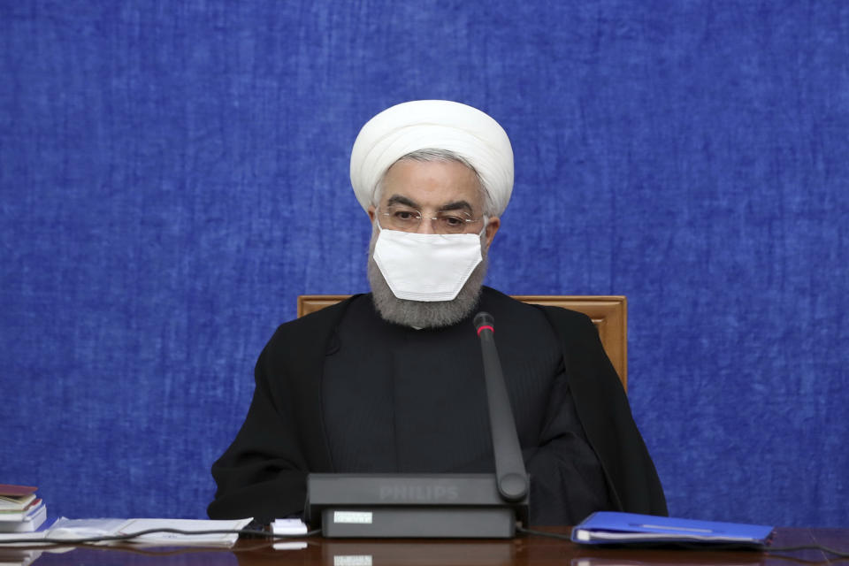 In this Oct. 13, 2020, photo, released by the official website of the office of the Iranian Presidency, President Hassan Rouhani wearing a protective face mask to help prevent spread of the coronavirus attends a meeting in Tehran, Iran. Iran is confronting a new surge of infections that is filling hospitals and cemeteries alike. Weeks after Rouhani called in-person instruction at schools “our first priority,” the government shut the newly resumed schools and universities in the capital. (Office of the Iranian Presidency via AP)