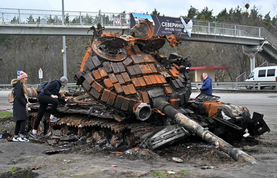 TOPSHOT - Residents look at a destroyed Russian tank on the outskirts of Buzova village, west of Kyiv, on April 10, 2020. (Photo by Sergei SUPINSKY / AFP) (Photo by SERGEI SUPINSKY/AFP via Getty Images)