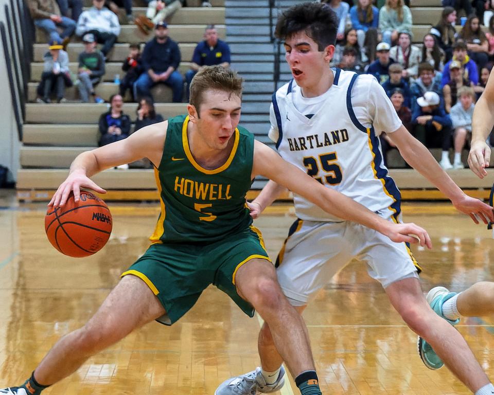 Howell's Logan Leppek (5), who scored a game-high 14 points, handles the ball while defended by Hartland's Brady Quinn (25) during the Highlanders' 55-27 victory Friday, Jan. 27, 2023.