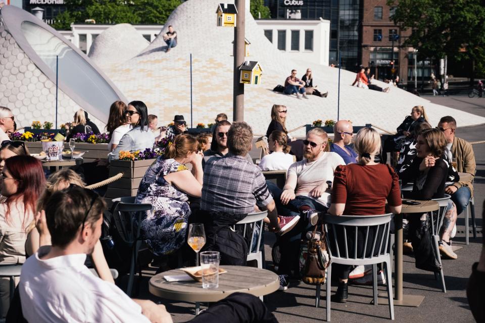 People are seen seated in chairs at an outdoor cafe.