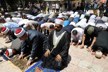 Palestinians pray as Israeli police officers look on by newly installed metal detectors at an entrance to the compound known to Muslims as Noble Sanctuary and to Jews as Temple Mount in Jerusalem's Old City July 16, 2017. REUTERS/Ammar Awad