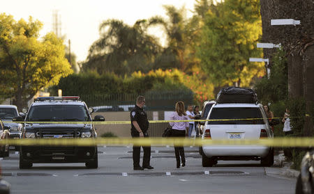 A police officer and residents are seen at the crime scene where mayor of Bell Gardens, California Daniel Crespo was shot, at a condominium in Bell Gardens, California September 30, 2014. REUTERS/Bob Riha