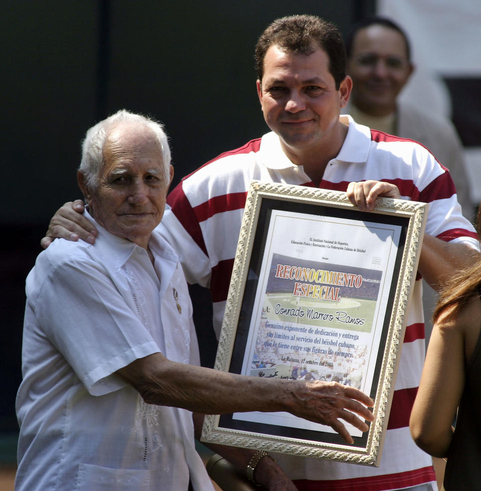 FILE - In this Oct. 12, 2003 file photo, Cuban pitcher Conrado Marrero, left, receives an award from Cuban President of the Sport Institute Humberto Rodriguez during the opening ceremony of the 35th baseball world championships in Havana, Cuba. Family members say Conrado Marrero, the oldest living former Major League Baseball player, has died in Havana. He was 102, just two days short of his 103rd birthday. Grandson Rogelio Marrero confirmed the death Wednesday afternoon, April 23, 2014. (AP Photo/Jose Goitia, File)